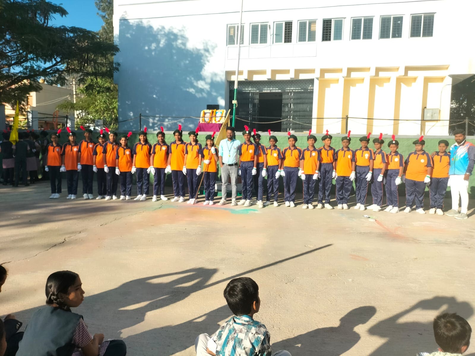 Students in orange and navy uniforms lined up in front of the school building